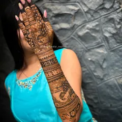 A stunning full-arm mehendi for an engagement bride. The design incorporates bold peacock figures, a classic symbol of grace and beauty in Indian culture, combined with intricate geometric bands for a balanced and striking look.