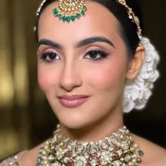 A close-up of the flawless bridal glam on my doctor bride. The makeup features soft, blended eyeshadow and a natural pink lip, complementing her pastel lehenga and intricate polki jewelry.