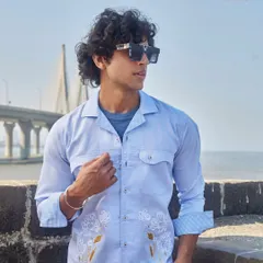 This light blue linen shirt with delicate floral embroidery offers a seamless blend of comfort and sophistication, perfect for a stylish day out by the sea.