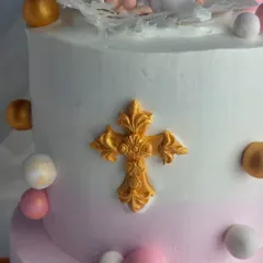 A detailed shot of the golden cross accent on the baptism cake.