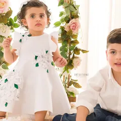A candid moment between siblings. The little girl sits on a floral swing while her brother joins her on the floor for this sweet portrait.