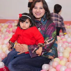 A mother and her young child share a happy moment together in the colorful ball pit.