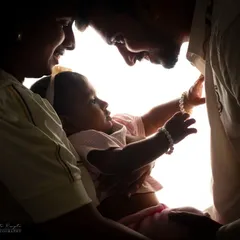 A beautiful backlit silhouette of parents admiring their baby, a perfect way to capture the love surrounding a new milestone.