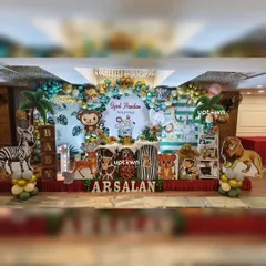 We transform any venue into a vibrant jungle with our detailed safari party setups. This decoration features a full stage with multiple animal cutout's, including a zebra and lion, palm tree prop's, and a dense balloon arch in shades of green and gold.