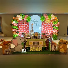 Welcome to Ayan's safari! This setup for a second birthday features a jeep-shaped main table, friendly animal cutouts like a large elephant and tiger, and a giraffe-print backdrop framed by a beautiful organic balloon garland.