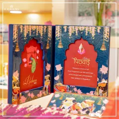 Here is a closer look at the Pichwai invitation box. The design features a window or 'jharokha' that frames the central motif, with text explaining the beautiful heritage of Pichwai art, making it both an invitation and a piece of cultural storytelling.