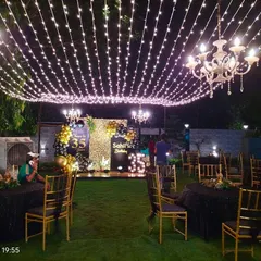 This outdoor 35th birthday party was transformed into an elegant evening affair with a canopy of warm string lights and classic chandeliers. The stage featured a personalized backdrop with marquee numbers, creating a sophisticated atmosphere for a large-scale celebration.