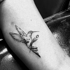 A small, beautifully detailed hummingbird tattoo on the inner arm. Even in a small size, we can capture the delicate features of the bird and flower.
