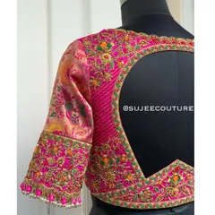 A beautiful example of a mixed-media back design. This pink blouse features a large circular cutout framed with vibrant, multi-colored floral embroidery that contrasts with the brocade sleeves.