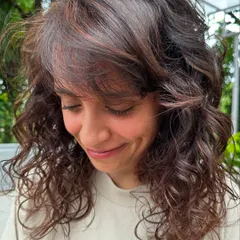 Curly and proud. I gave her curls a new life with a fresh cut, including a fringe, and subtle reddish-brown highlights to define the texture. Embracing your natural curls is always a good idea.