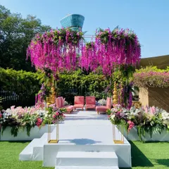 We wrapped this outdoor mandap in vibrant pinks, purples, and lush greens. The cascading wisteria and dense florals create a feeling of being in a magical garden, a perfect setting for two souls to say forever.