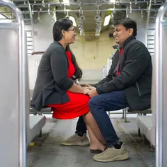 A candid and happy moment from a conceptual pre-wedding shoot inside a Mumbai local train, capturing a couple's love story.
