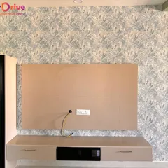 An accent wall can redefine a living space. Here, I installed a subtle botanical leaf pattern wallpaper behind a TV unit, adding a touch of modern elegance and texture that complements the room's neutral furniture.