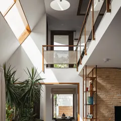 In this double-height living area, we used large skylights to drench the space in natural light. The light plays off the stone wall and nourishes the tall indoor plants, effectively erasing the boundary between the interior and the sky.