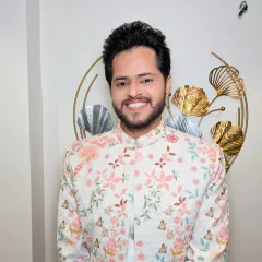 A close-up of the groom's happy face. The light-colored, floral outfit is complemented by a bright and natural makeup look.