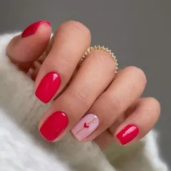 A beautiful red manicure with a single accent nail featuring a minimalist love letter design.
