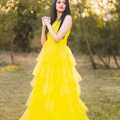 A full-length shot of the yellow tiered gown, showing its flowing A-line silhouette. It's a versatile piece that allows for a variety of poses for models and influencers.