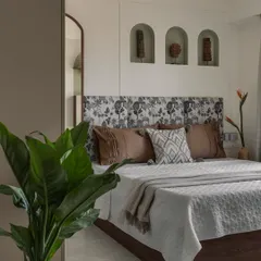 A closer look at the bedroom, focusing on the custom headboard with its unique print and the arched wall niches that display curated decor pieces, adding a personal touch.