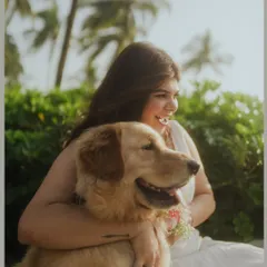 A joyful, candid shot of the bride laughing as she hugs her happy golden retriever on a sunny beach. This photo perfectly captures the special bond between a pet parent and their dog.