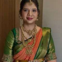 A frontal portrait of a beautiful South Indian bride. Her look features expertly blended eyeshadow and a rich lip color, complementing the intricate temple jewellery and embroidered blouse.