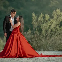 A quiet moment of connection amidst the grandeur. Even with a dramatic flowing gown, the focus remains on the couple's chemistry, captured against the natural, sandy riverbank.