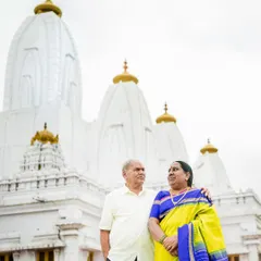 A majestic portrait of a couple celebrating their 50th anniversary, standing before a beautiful white temple, symbolizing their long and blessed journey together.