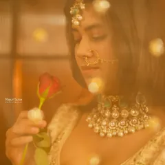 A dreamy and romantic bridal portrait. Using a soft focus and warm, glowing lights, this shot captures the bride in a quiet moment with a rose, creating a magical and ethereal feel.