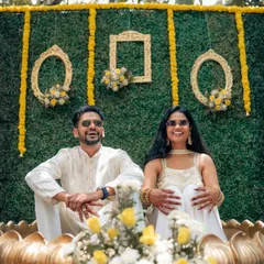 This couple is enjoying their Haldi against a custom-designed green wall accented with yellow marigolds and ornate golden frames. It’s a modern twist on a traditional ceremony, creating a unique photo opportunity.