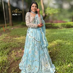 An ethereal Sangeet look in a blue mirror-work lehenga. The makeup is kept fresh and dewy, with a unique braided hairstyle that incorporates mirror details.