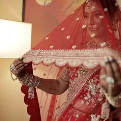 The bridal veil or ghunghat shot is iconic. The makeup is applied to look soft and radiant even when partially covered, creating a sense of mystery and elegance.