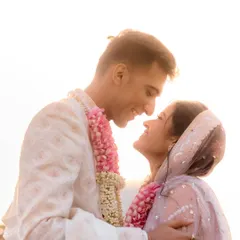 A sun-kissed portrait just after the ceremony. The golden light beautifully backlights the couple, creating a halo effect that emphasizes their newly married glow and the love in their eyes.