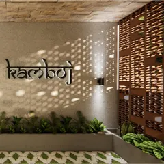 This image highlights the custom signage and jali partition at the clinic entrance. The name "Kamboj" is mounted on a stone-clad wall, with a decorative screen that allows sunlight to cast intricate patterns, blending branding with artistic detail.
