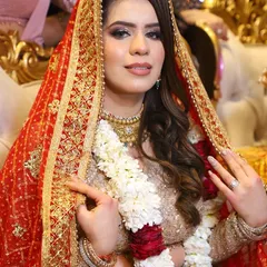 A beautiful bride with a soft, glowing makeup look. The focus is on flawless skin and defined eyes, perfect for her elegant gold and red outfit.