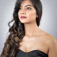 An unapologetic and confident portrait. The simple strapless top and voluminous hair are styled to draw all attention to the model's face and her calm, self-assured expression.