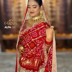 This pose showcases the rich detail of the bridal outfit and jewelry. The makeup features soft, shimmering eyes and a defined lip to complete the traditional aesthetic.