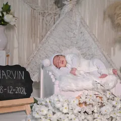 A classic all-white newborn setup. This clean and timeless look includes a small bed, soft blankets, and a personalized slate to announce your baby's name and birth date, creating a beautiful keepsake.
