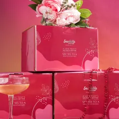 This shot focuses on the special edition Valentine's packaging. Stacking the boxes and styling them with flowers and a cocktail glass creates an elegant and celebratory image, perfect for promoting a limited-time offer.