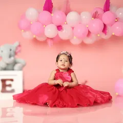 It's her first birthday! This little princess looks so beautiful in her red dress, surrounded by pink balloons. A perfect birthday portrait.