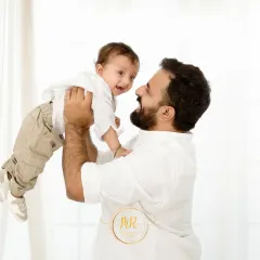 A joyful father lifts his baby high in the air. This dynamic shot, part of a light and airy session, perfectly captures the fun and energy of family life.