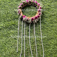 A fresh floral hair tiara designed for a Haldi bride. This piece features purple flowers and baby's breath with long, delicate pearl tassels that cascade down the hair.