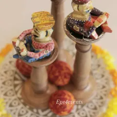 An overhead view of the traditional Rajasthani centerpiece, showing the intricate details of the painted musician figurines and the circular arrangement of marigold petals on a patterned base.