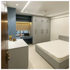 This bedroom design blends a cool grey-blue Duco finish with warm laminate textures. We created a functional layout with a full-wall wardrobe, a compact study desk by the window, and clean, linear cove lighting.