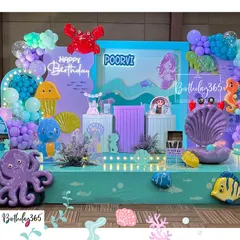 A vibrant "Under the Sea" party for Poorvi. The stage was filled with colorful sea creatures like an octopus and crab, a large seashell, and a beautiful mermaid backdrop.
