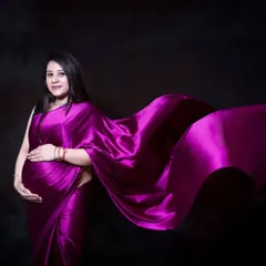 The rich color and sheen of this satin saree look incredible against a dark studio background. It's a beautiful way to celebrate your heritage during your maternity photoshoot.