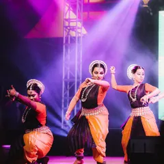 A trio of Odissi dancers performs in perfect harmony under dramatic purple spotlights. I focus on capturing the powerful expressions and intricate movements of classical dance forms.