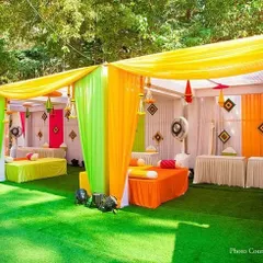 I bring energy to your Mehendi ceremony with vibrant outdoor setups. This decor uses a bright color palette of yellow, green, and orange drapes, with comfortable low diwan seating and festive hangings for a fun, celebratory vibe.
