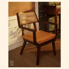 A vintage soul with modern comfort. This armchair features a dark-stained teak frame, a woven cane back, and a comfortable tan leather seat, embodying quiet sophistication.