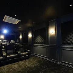 The projector beam cuts through the darkness, highlighting the luxurious details of the room, including the starlit ceiling and the rich, black tufted wall panels.