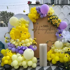 A sweet "A Little Honeybee is on the Way" themed baby shower. This outdoor setup uses yellow and purple balloons to create honeycomb and bee shapes, with sunflower accents adding to the charm.