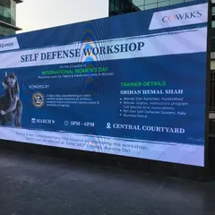 The event banner for our Self Defense Workshop at a corporate park, displayed on a large screen for International Women's Day.